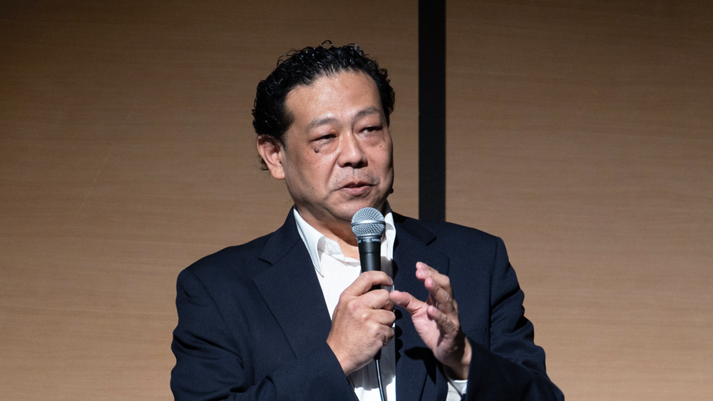 マイクを持って講演する男性