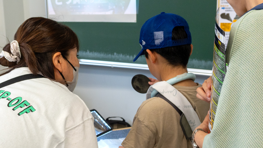 銅鏡の鏡面をのぞき込む少年と見守る大人たち