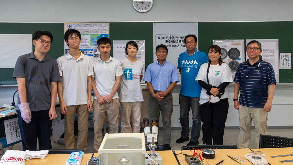 大学の教室の黒板の前で並んだ8人の写真　イベントの前の記念撮影