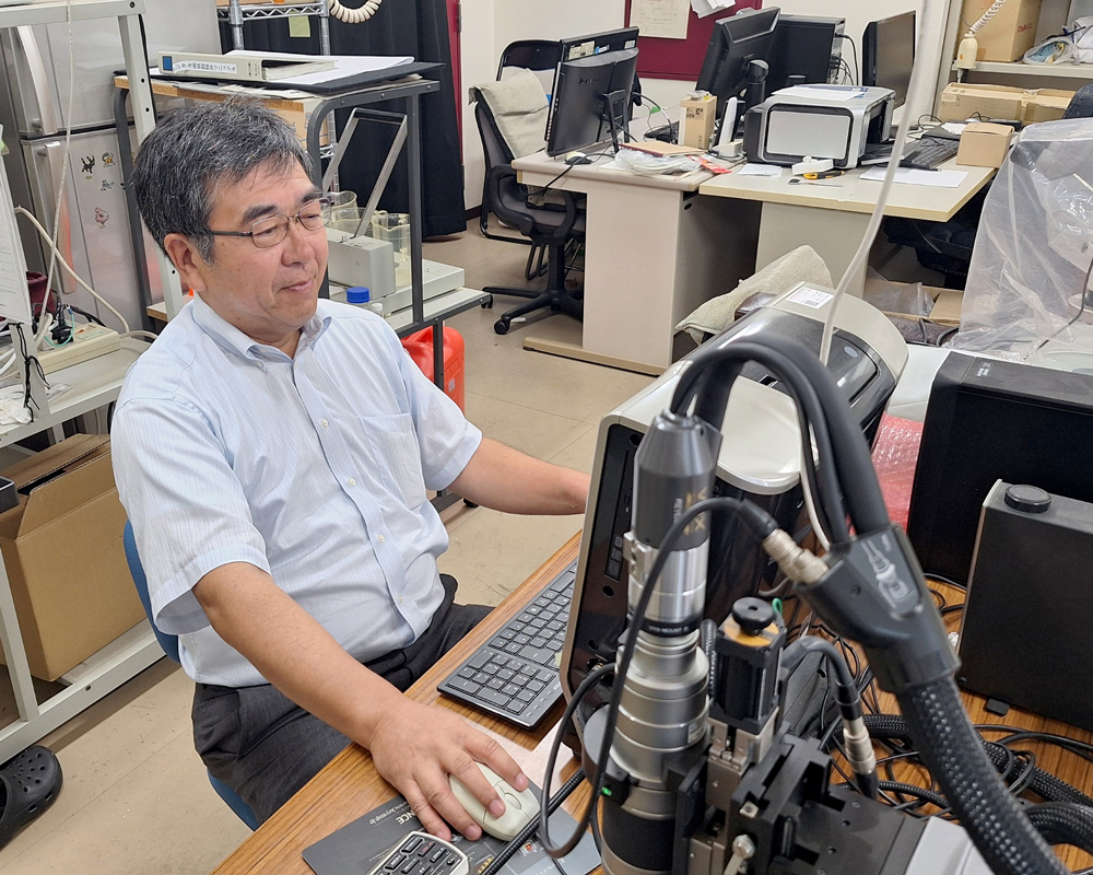 顕微鏡付属のモニターを見ながら操作する男性