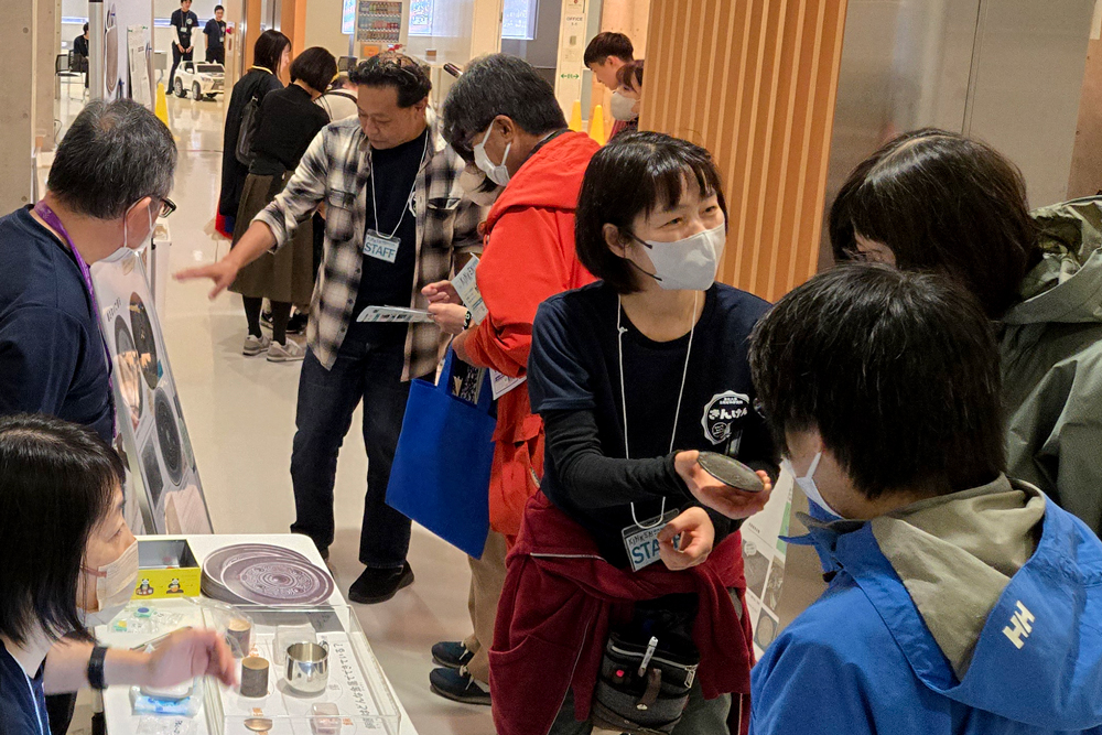 来場者に銅鏡を手に持ってみるよう勧めているようす