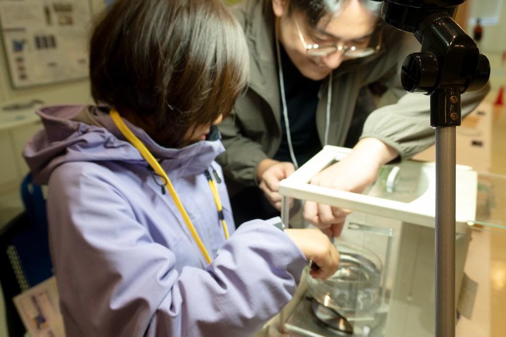 密度測定器の部品を水中に落としてしまい拾っている子ども