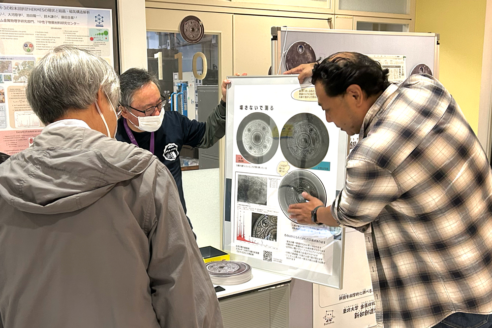 ポスターパネルを使って銅鏡のX線CT像について説明しているようす