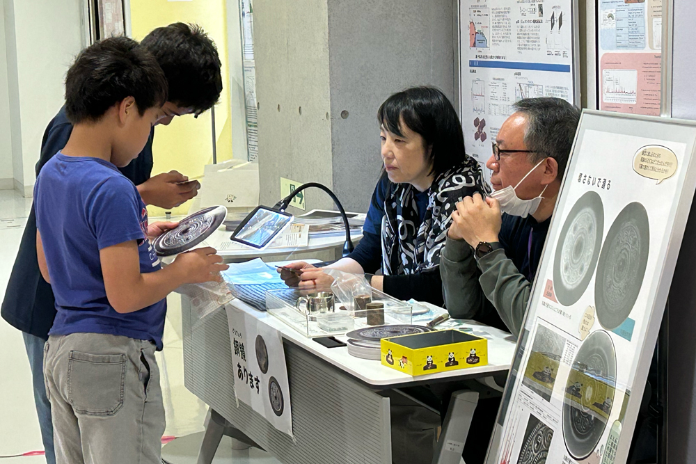 来場者が銅鏡と銅鏡うちわを見ているようす