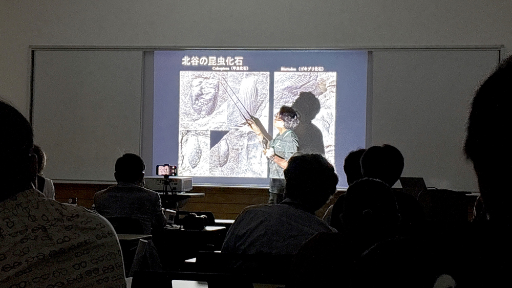 スライドを棒で指している男性と聞いている人たち