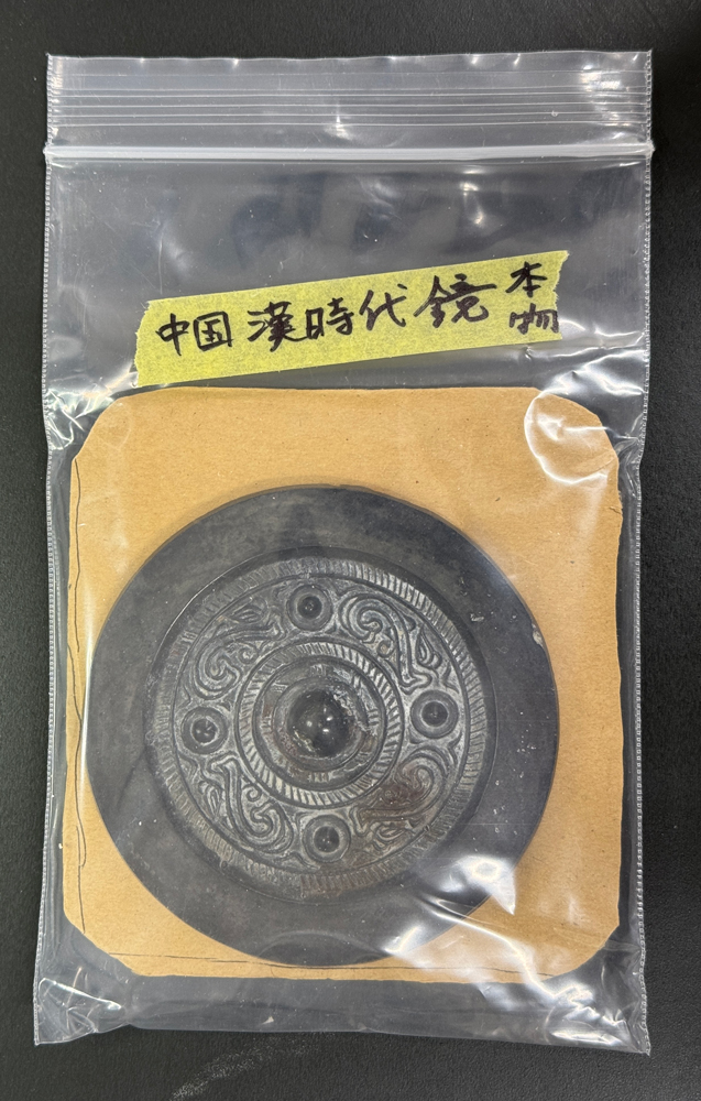 チャック付き袋に入れられた銅鏡「中国　漢時代　鏡　本物」と書かれたマスキングテープが貼ってある