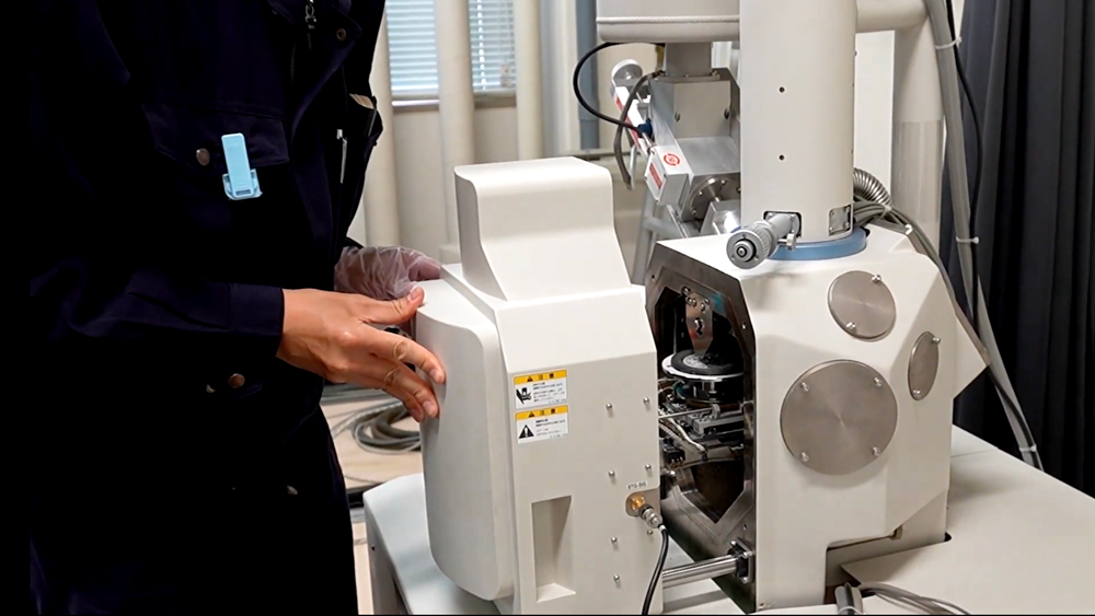 SEMの試料室のドアを手で閉めるようす