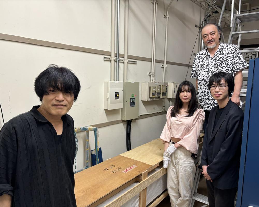 細長い木枠の周りに人が立ち笑顔を見せている写真