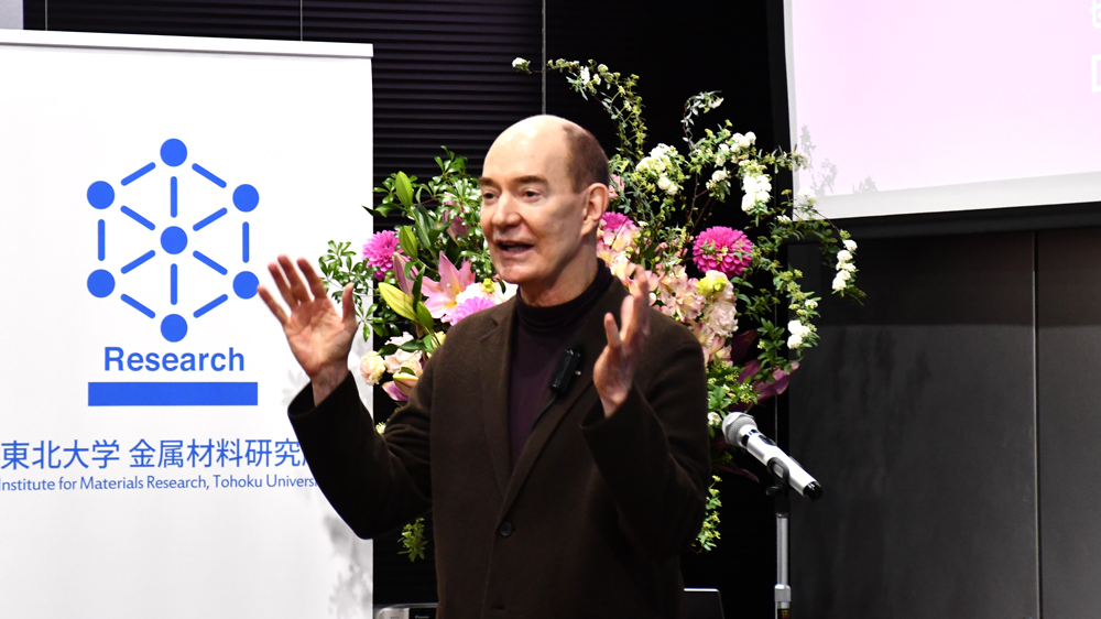 壇上で両手を上げながら話す男性