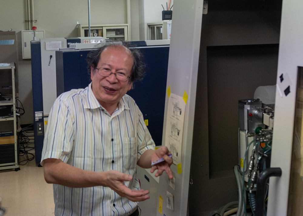 実験装置の傍で説明する男性