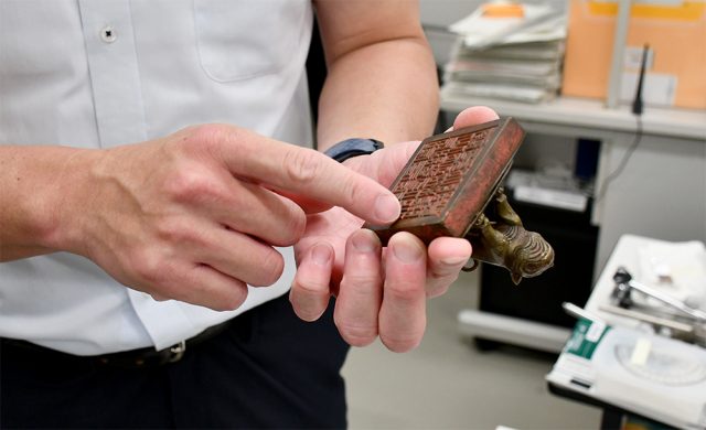金属でできた大きな虎のハンコを手にする男性