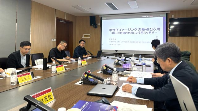 会議室でスクリーンを挟んで向かい合って座る参加者達のようす スクリーンには、「中性子イメージングの基礎と応用」と書かれている
