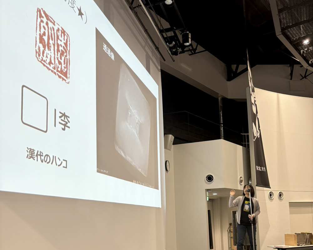 スクリーンの前で発表する人