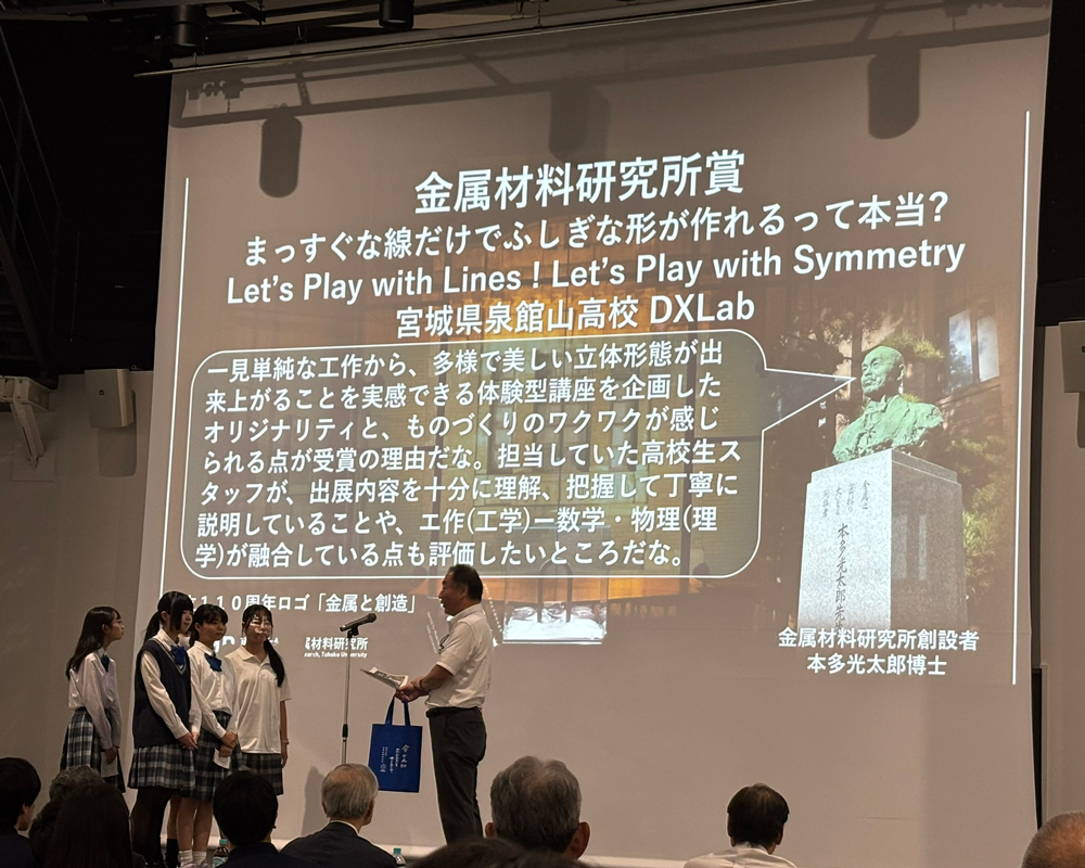 スライドに映し出された本多光太郎の銅像がコメントを発している下で、高校生4人に賞を渡す男性