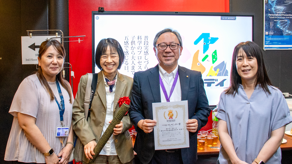 「サイエンスデイ」と映し出されたモニターの前に並び笑顔を見せる人々