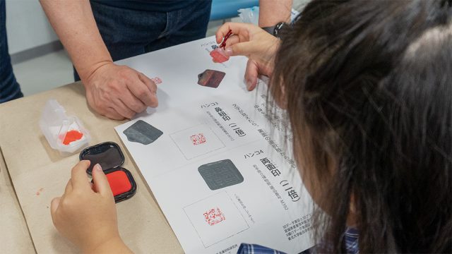 プリントにハンコを押す子どもの後ろ姿