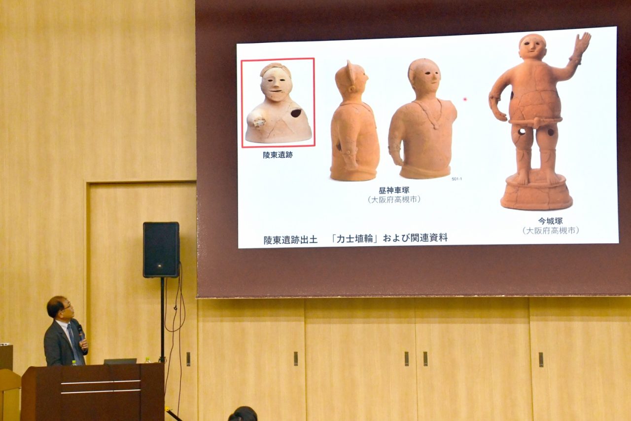 壇上でスライドを見上げながら話す男性