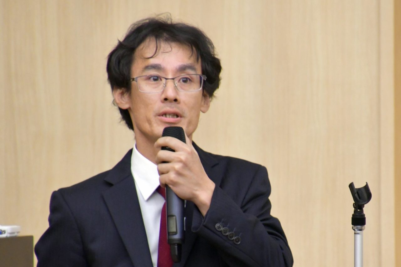 壇上でマイクを握って話す男性