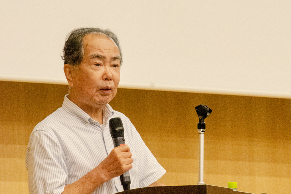 壇上でマイクを握って話す男性