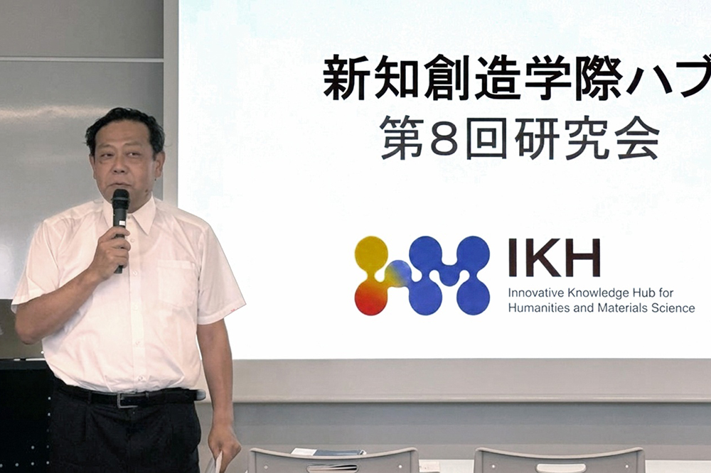 マイクを持って話している男性と「新知創造学際ハブ第8回研究会」と映し出されたスクリーン